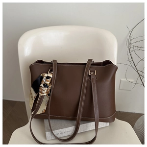 Detail of dark brown tote bag with white contrast stitching and decorative silk scarf