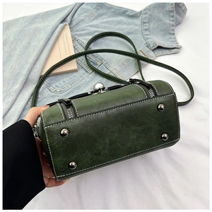 Detail of green cylinder shoulder bag with silver sphere clasp and white contrast stitching