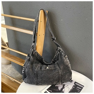 Detailed view of washed black denim shoulder bag with multiple pockets and metal buckles