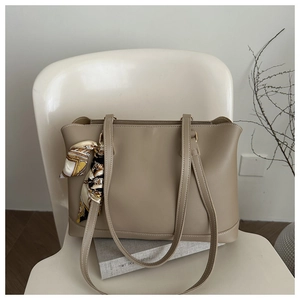 Close-up of khaki tote bag with a decorative silk scarf on a white chair