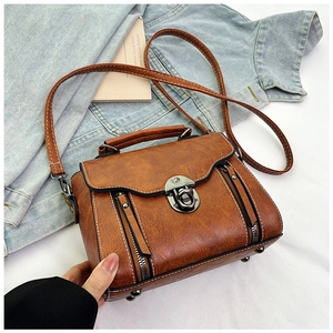 Close-up of vintage brown PU crossbody bag with metal twist lock and white stitching detail