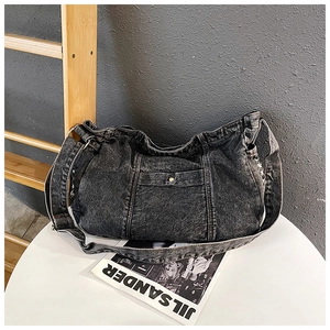 Detail of dark gray washed denim crossbody bag featuring vintage metal button closure