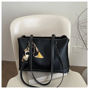 Close-up of black leather tote bag with white stitching and decorative silk scarf