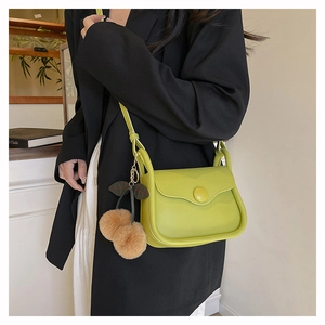 Lime green flap crossbody bag with plush cherry pendant shown on dark blazer