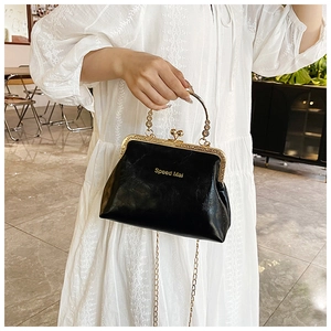 Dettaglio borsa vintage nera con chiusura a scatto, manico dorato e tracolla a catena