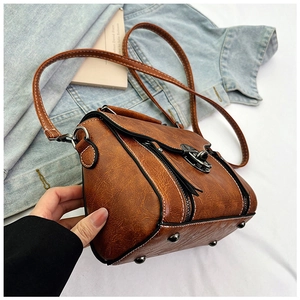 Detail view of brown vintage satchel with contrast stitching and metal twist-lock