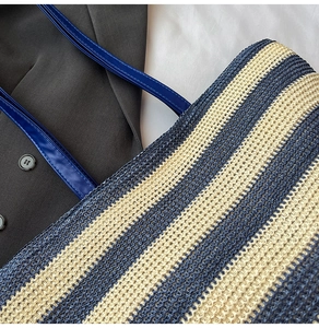 Détail de la texture tissée du sac fourre-tout rayé bleu et beige avec anse en cuir