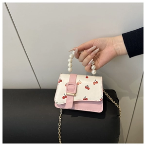 Detail of pink and white crossbody bag with cherry prints and large pearl handle