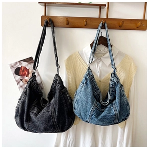 Detail view of large denim hobo bags in vintage grey and blue hanging on a wooden rack