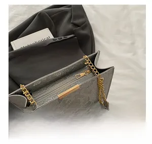 Detailed view of the smooth golden zipper and grey snakeskin texture on the bag