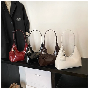 Row of four glossy patent leather baguette underarm bags with heart pendants in rich colors