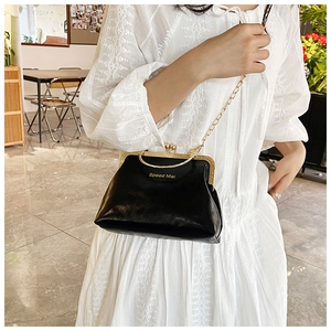 Dettaglio borsa vintage nera con catena dorata e manico in metallo su vestito bianco