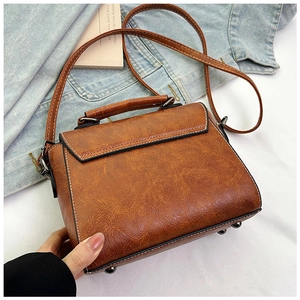 Close-up of vintage brown PU leather texture and sturdy hand strap on retro crossbody bag