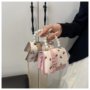 Detail of mini bags with pearl handles, cherry prints, and gold chain straps