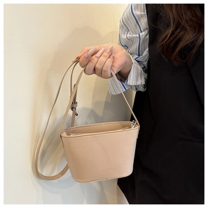 Detail of beige PU leather mini bucket bag with embossed logo and silver zipper