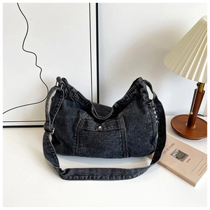 Close-up of black denim hobo bag with thick stitching and front metal buckle detail