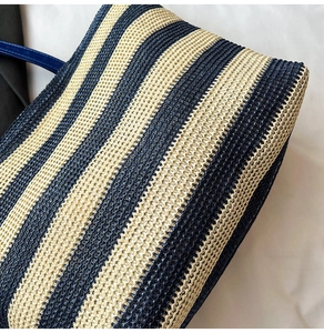 Détail du sac fourre-tout rayé bleu et beige avec texture tressée et anses en cuir