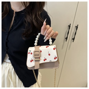 Detail of white pearl handle and red cherry print on small crossbody bag for women