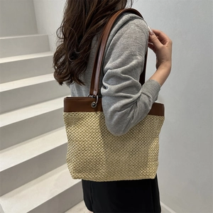 Fashionable straw woven tote bag with brown leather straps shown on a model