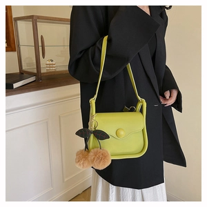 Detail of yellow crossbody bag with brown faux fur cherry charm on black blazer