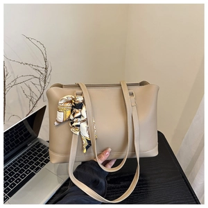 Detail of beige faux leather tote with decorative patterned silk scarf on handle