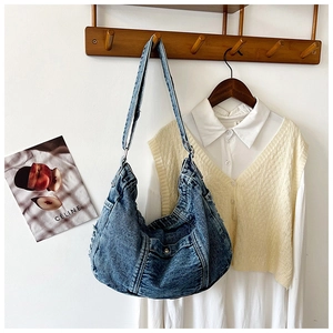 Detail of vintage washed denim hobo bag featuring contrast stitching and magnetic closure