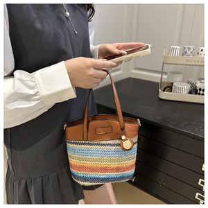 Détail du sac seau en paille à rayures arc-en-ciel avec poignées en cuir et breloque