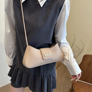 Minimalist beige baguette shoulder bag with metal buckle shown on a model in a modern style