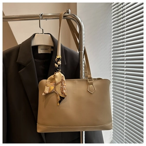 Close-up of khaki leather tote bag with a vintage silk scarf on a metal hanger