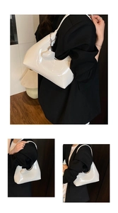 Close-up of white glossy patent leather hobo bag with heart charm and metal chain