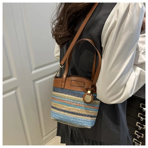 Détail du sac seau tissé coloré avec bandoulière en cuir et plaque logo en métal