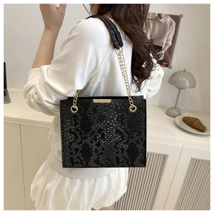 Detail of black snakeskin pattern tote bag with gold metal trim and chain strap