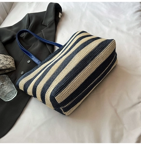 Détail du sac cabas rayé tissé avec anses en cuir sur fond blanc minimaliste