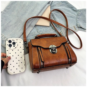 Detail of vintage brown PU leather crossbody bag with silver twist lock and retro texture
