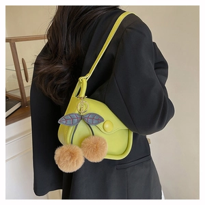 Detail view of lime green crossbody bag with a cute plush cherry charm on a black blazer