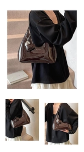 Detail of dark brown patent leather baguette bag with silver chain and heart charm