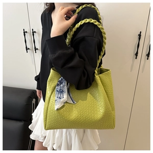 Détail du sac cabas vert avec texture embossée et foulard en soie bleu sur la poignée