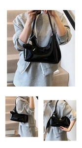 Detail of black patent leather underarm bag with glossy finish and heart pendant