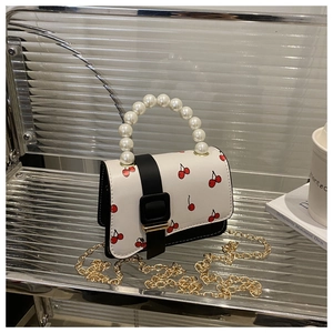 Close-up of mini cherry print bag with large pearl handle and gold chain strap