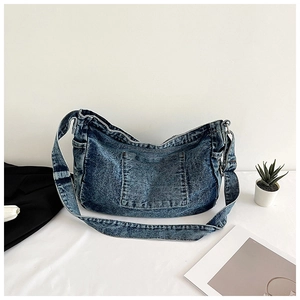 Detail of vintage washed denim tote bag showing distressed texture and functional front pocket