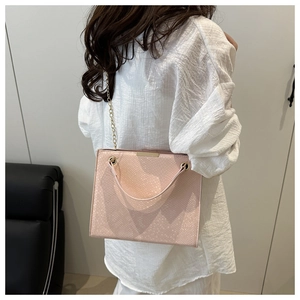 Detail of light pink snake-embossed leather handbag with elegant gold chain strap