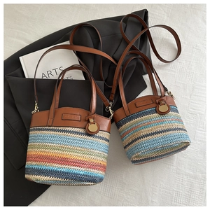 Détail du sac seau en paille à rayures colorées avec anse et bandoulière en cuir brun