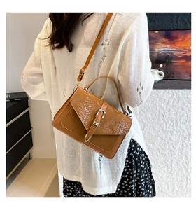 Detailed view of brown snake-embossed leather handbag with vintage metal clasp and long strap