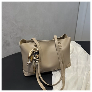 Detail of elegant beige tote bag with chic geometric silk scarf tied on the handle