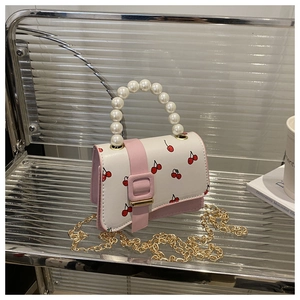 Detail of pearl handle and cherry print on a stylish white and pink crossbody handbag