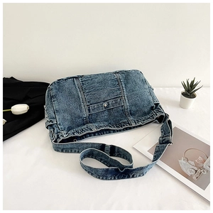 Flat lay of retro blue denim crossbody bag with metal button detail and broad strap