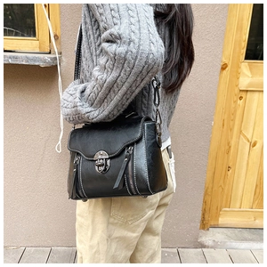 Detail of vintage black crossbody bag with white stitching and silver metal clasp lock