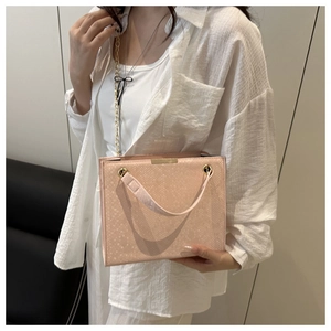 Close-up of pink snake pattern handbag with gold chain strap on a fashion model
