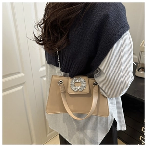 Elegante borsa in pelle beige con fibbia di cristallo indossata da una modella in outfit