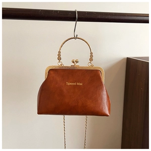 Dettaglio borsa vintage in pelle marrone con manico dorato floreale e chiusura clic-clac